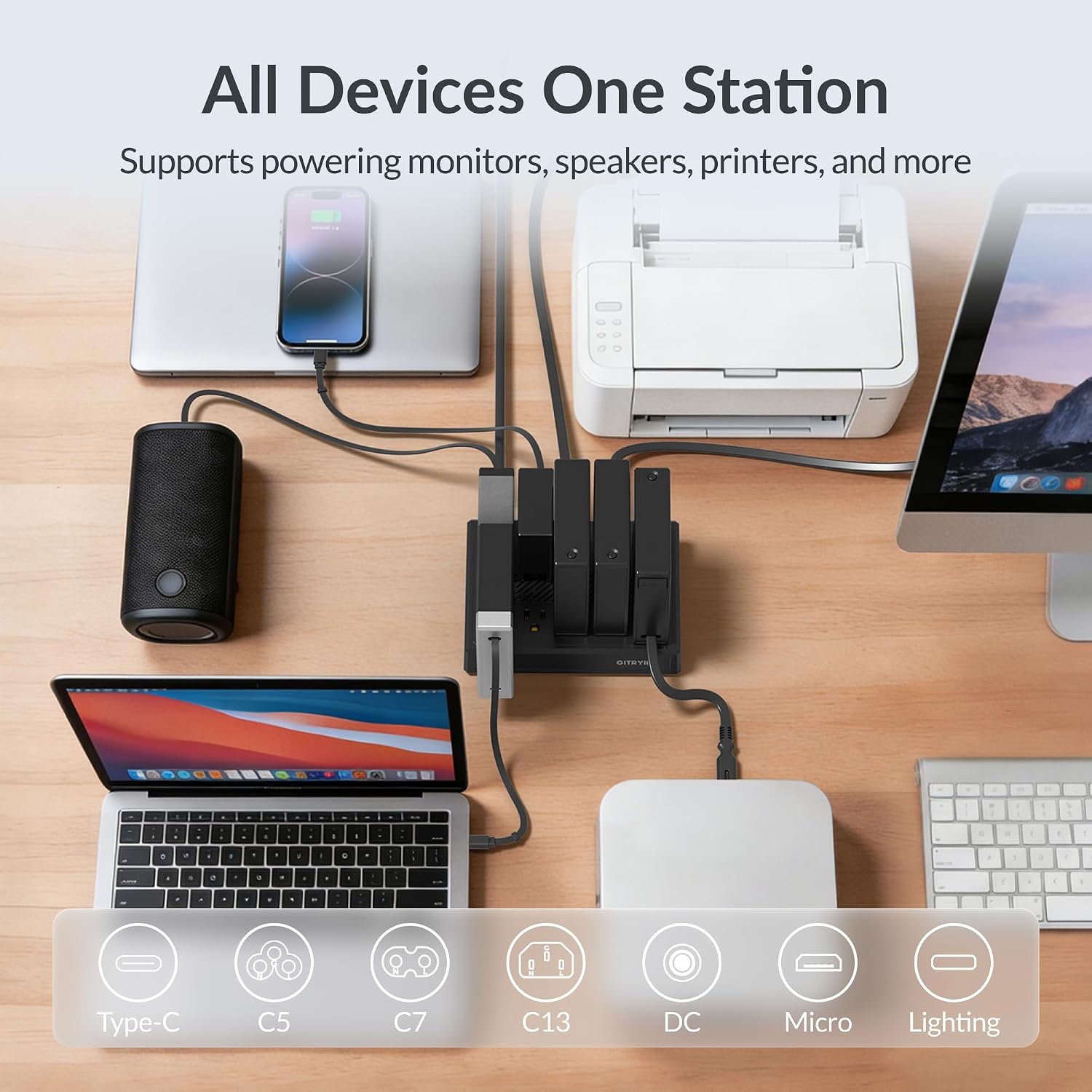 Laptop charging hub on a desk corner in a home office next to a laptop and lamp
